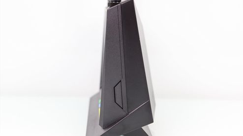 Vista de perfil de un router inalámbrico ASUS RT-AX86U de color negro sobre fondo blanco.
