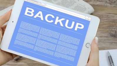 Tableta blanca que muestra en pantalla la palabra BACKUP sobre un fondo azul con texto descriptivo.