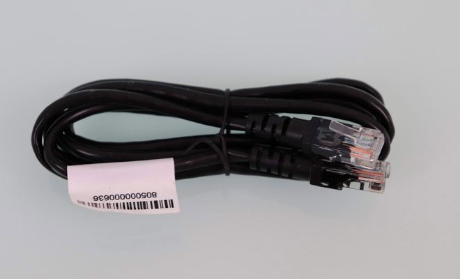 Cable Ethernet negro enrollado con conectores RJ45 y etiqueta blanca de código de barras.