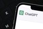 Primer plano de la interfaz de ChatGPT en la pantalla de un smartphone situado junto a un teclado de ordenador.