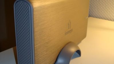 Disco duro externo Iomega de sobremesa con carcasa metálica dorada y soporte vertical gris.