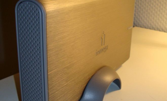 Disco duro externo Iomega de sobremesa con carcasa metálica dorada y soporte vertical gris.