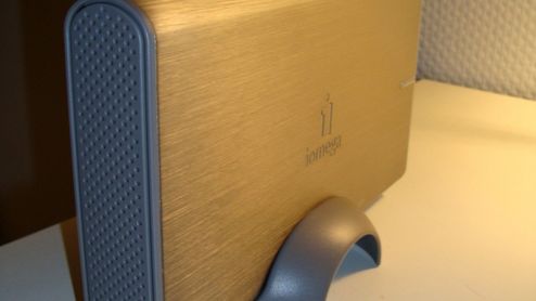 Disco duro externo Iomega de sobremesa con carcasa metálica dorada y soporte vertical gris.