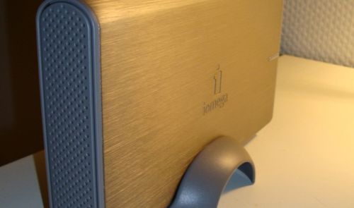 Disco duro externo Iomega de sobremesa con carcasa metálica dorada y soporte vertical gris.