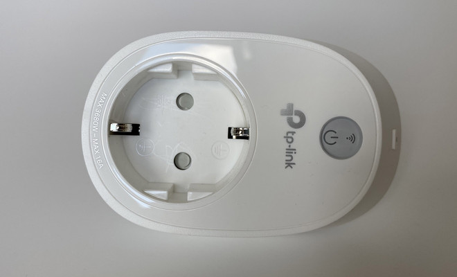 Primer plano de un enchufe inteligente TP-Link de color blanco con botón de encendido físico.