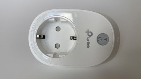 Primer plano de un enchufe inteligente TP-Link de color blanco con botón de encendido físico.