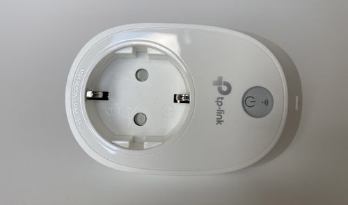 Primer plano de un enchufe inteligente TP-Link de color blanco con botón de encendido físico.