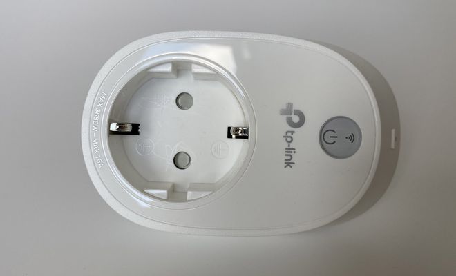Primer plano de un enchufe inteligente TP-Link de color blanco con botón de encendido físico.