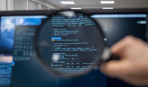 Una lupa amplía líneas de código informático en la pantalla de un monitor para detectar errores.