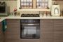 Cocina moderna con encimera blanca, fogones de gas, horno integrado y mobiliario de madera laminada.