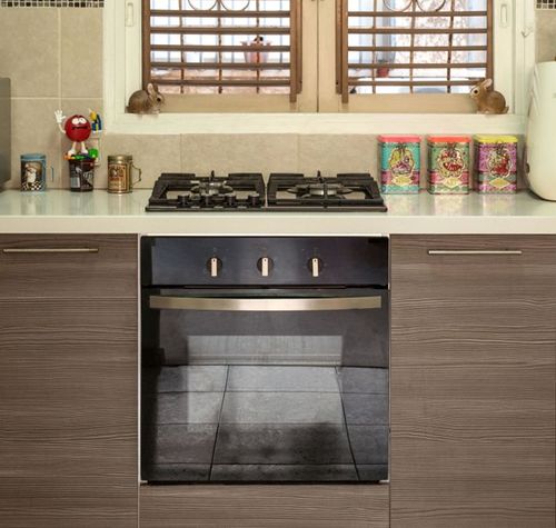 Cocina moderna con encimera blanca, fogones de gas, horno integrado y mobiliario de madera laminada.