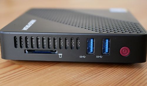 Panel frontal de un mini PC de color negro con puertos USB 3.0, lector de tarjetas SD y botón de encendido rojo.