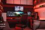 Habitación tipo setup gaming con varios monitores, torre de PC iluminada y consola, en un entorno con luces LED rojas.