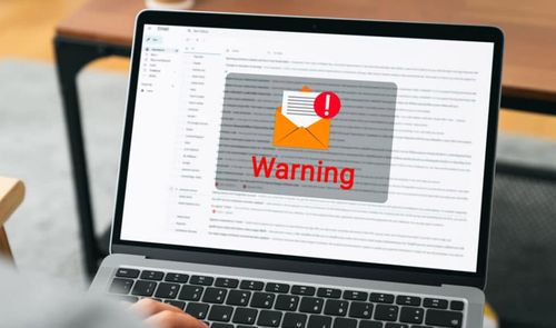 Pantalla de ordenador portátil mostrando un correo electrónico con un aviso de advertencia de seguridad superpuesto.