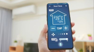 Mano sujetando un teléfono móvil con una aplicación de Smart Home abierta para controlar la temperatura del hogar.