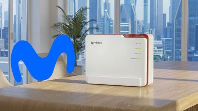 Router FRITZ!Box sobre una mesa de madera junto al logotipo de Movistar con vistas a una ciudad de fondo.