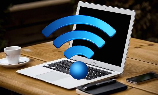 Ordenador portátil abierto sobre una mesa de madera con un gran símbolo tridimensional de Wi-Fi azul delante de la pantalla.