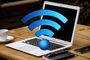 Ordenador portátil abierto sobre una mesa de madera con un gran símbolo tridimensional de Wi-Fi azul delante de la pantalla.