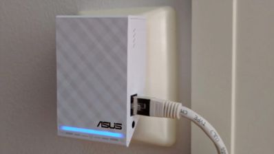 Repetidor Wi-Fi ASUS blanco con cable Ethernet conectado y luz LED azul encendida.
