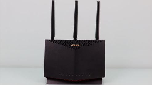 Router ASUS RT-AX86U visto de frente con sus tres antenas externas sobre un fondo blanco.