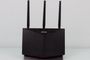 Router ASUS RT-AX86U visto de frente con sus tres antenas externas sobre un fondo blanco.
