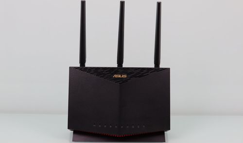 Router ASUS RT-AX86U visto de frente con sus tres antenas externas sobre un fondo blanco.