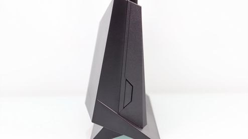 Vista lateral del router ASUS RT-AX86U que muestra su perfil angular y el botón lateral sobre un fondo blanco.