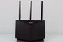 Router inalámbrico ASUS RT-AX86U de color negro con tres antenas externas sobre una superficie blanca.