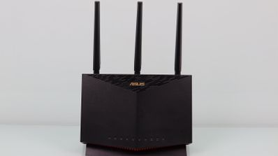 Router inalámbrico ASUS RT-AX86U de color negro con tres antenas externas sobre una superficie blanca.