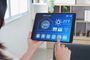 Persona utilizando una aplicación de Smart Home en una tablet para gestionar la temperatura y la humedad del hogar.