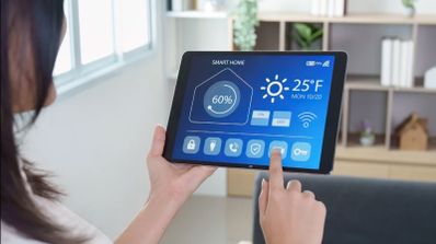 Persona utilizando una aplicación de Smart Home en una tablet para gestionar la temperatura y la humedad del hogar.