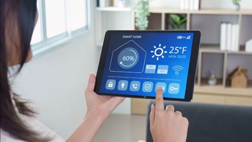 Persona utilizando una aplicación de Smart Home en una tablet para gestionar la temperatura y la humedad del hogar.