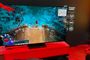 Televisor de gran formato mostrando una partida de videojuego de rol en un entorno de exposición con iluminación roja.