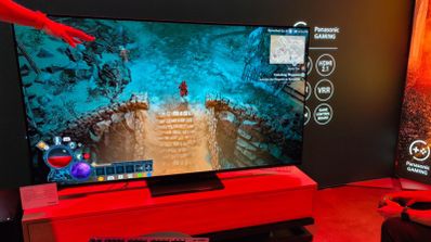 Televisor de gran formato mostrando una partida de videojuego de rol en un entorno de exposición con iluminación roja.