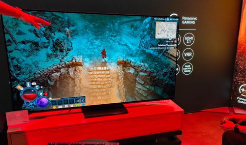 Televisor de gran formato mostrando una partida de videojuego de rol en un entorno de exposición con iluminación roja.