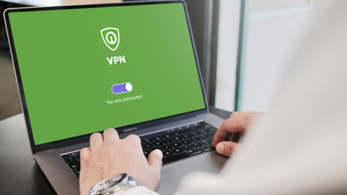 Persona utilizando un ordenador portátil con una aplicación de VPN conectada en pantalla.