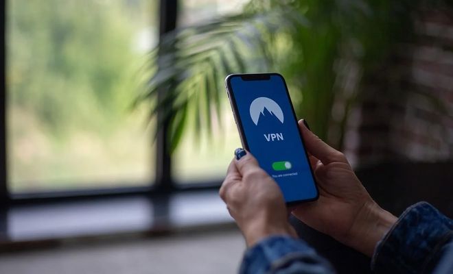 Persona sujetando un teléfono móvil con una aplicación de VPN activada en la pantalla.