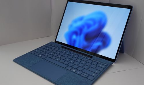 Ordenador portátil abierto sobre una mesa blanca con el fondo de pantalla azul de Windows 11.