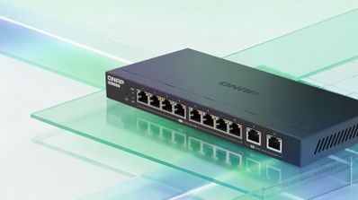 Switch de red QNAP QSW-2000 con diez puertos Ethernet frontales sobre una superficie de cristal.