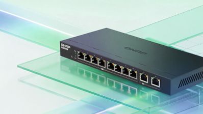 Switch de red QNAP QSW-2000 con diez puertos Ethernet frontales sobre una superficie de cristal.