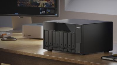 Unidad de almacenamiento QNAP TL-D810TC4 con ocho bahías frontales sobre un escritorio de madera.
