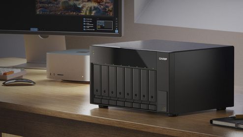 Unidad de almacenamiento QNAP TL-D810TC4 con ocho bahías frontales sobre un escritorio de madera.