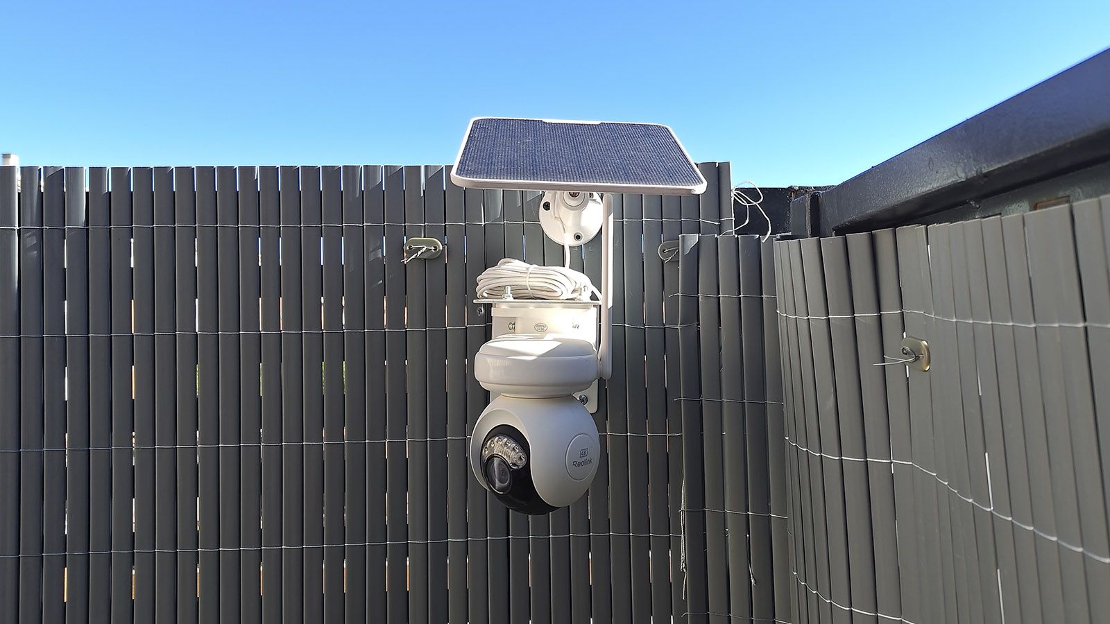 Cámara de vigilancia Reolink Altas PT Ultra instalada en una valla con panel solar superior.