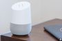 Altavoz inteligente de cuerpo blanco y base gris sobre una mesa de madera.