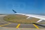 Ala de avión sobre la pista de rodaje del Aeropuerto de Melbourne con cielo despejado.