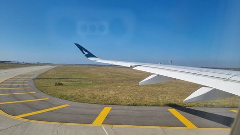Ala de avión sobre la pista de rodaje del Aeropuerto de Melbourne con cielo despejado.