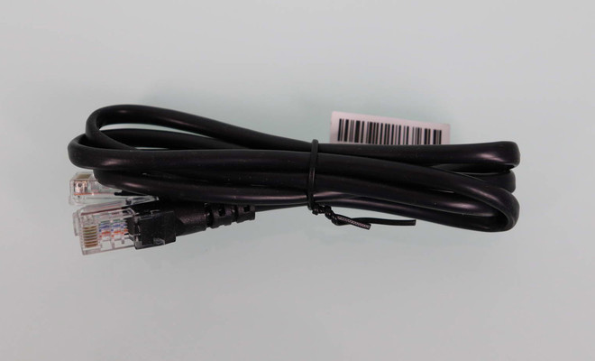 Cable Ethernet negro enrollado con conectores RJ45 y etiqueta de código de barras sobre un fondo claro.