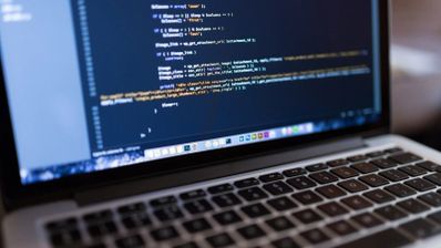 Primer plano de una pantalla de ordenador portátil que muestra líneas de código de programación en un editor con fondo oscuro.
