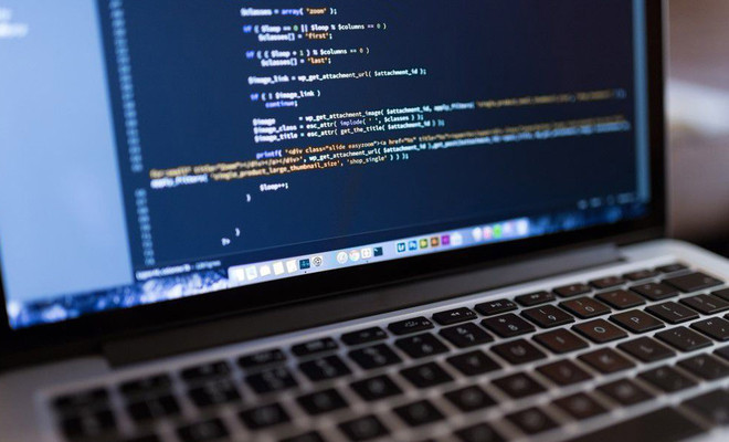 Primer plano de una pantalla de ordenador portátil que muestra líneas de código de programación en un editor con fondo oscuro.