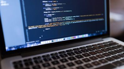 Primer plano de una pantalla de ordenador portátil que muestra líneas de código de programación en un editor con fondo oscuro.